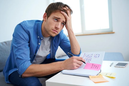 Парень сидит за столом с записками